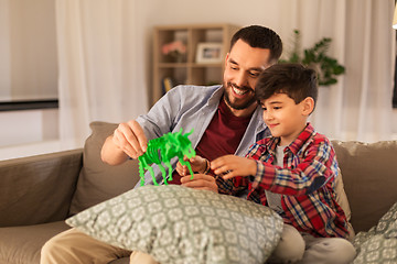 Image showing father and son playing with toy dinosaur at home