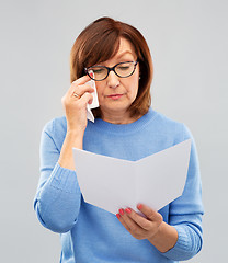 Image showing sad senior woman reading letter and crying