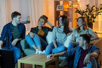 Image showing happy friends watching tv at home in evening