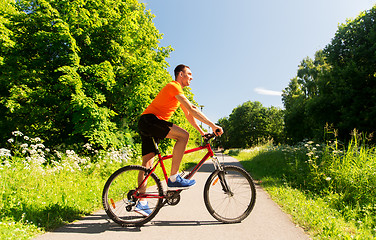 Image showing happy young man cycling by bicycle in summer park