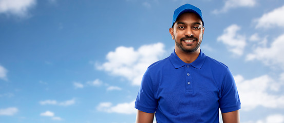 Image showing happy indian delivery man in blue uniform over sky