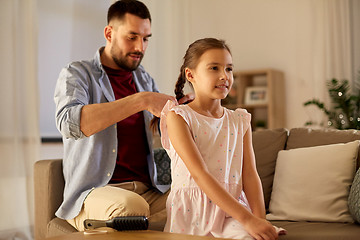 Image showing father braiding daughter hair at home