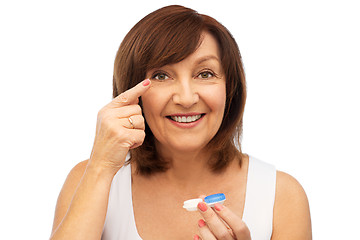 Image showing happy senior woman applying contact lenses