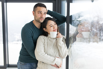 Image showing multiethnic couple enjoying morning coffee by the window