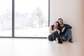 Image showing multiethnic couple sitting on the floor near window at home