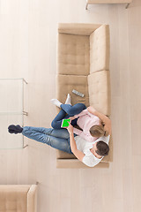 Image showing young couple in living room using tablet top view