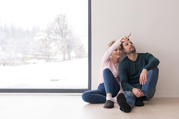 Image showing young couple sitting on the floor near window at home