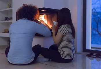 Image showing happy multiethnic couple sitting in front of fireplace