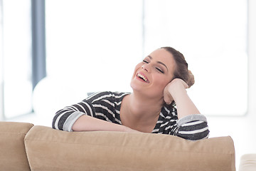 Image showing portrait of a young beautiful woman sitting on the sofa