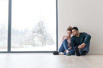 Image showing young couple sitting on the floor near window at home