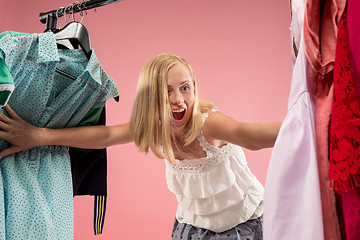 Image showing The young pretty girl looking at dresses and try on it while choosing at shop