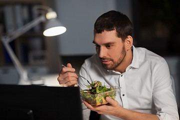 Image showing businessman with computer eating at night office