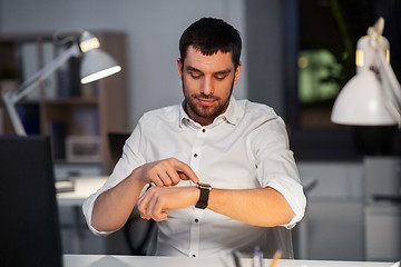 Image showing happy businessman with smart watch at nigh office