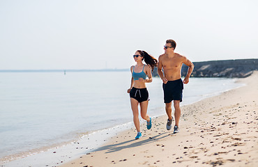 Image showing couple in sports clothes running along on beach