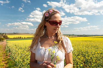 Image showing Country woman standing near fields of canola and wheat 