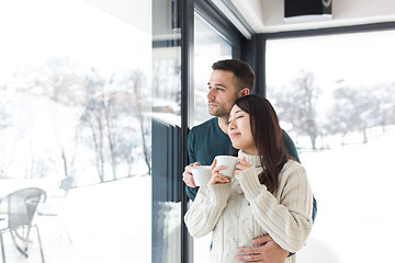 Image showing multiethnic couple enjoying morning coffee by the window