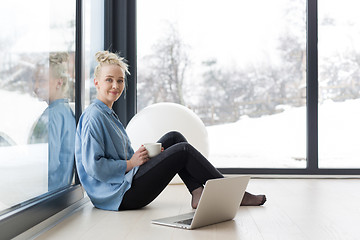 Image showing woman drinking coffee and using laptop at home