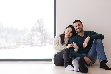 Image showing multiethnic couple sitting on the floor near window at home