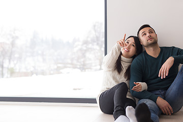 Image showing multiethnic couple sitting on the floor near window at home