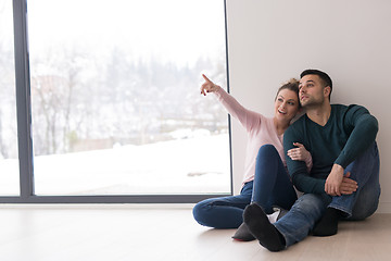 Image showing young couple sitting on the floor near window at home