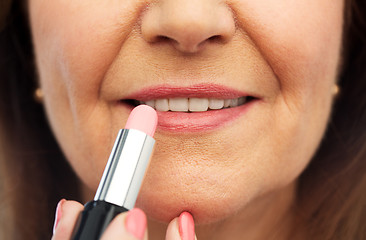 Image showing close up of senior woman applying lipstick