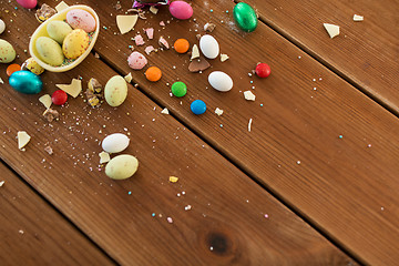 Image showing chocolate egg and candy drops on wooden table