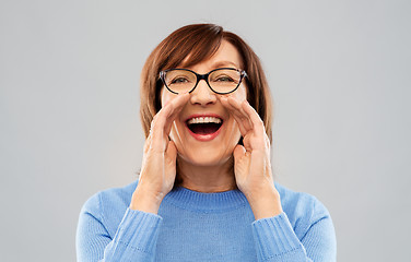 Image showing senior woman in glasses calling over grey