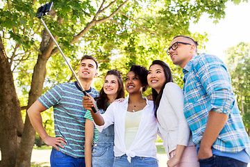 Image showing happy friends taking photo by selfie stick at park