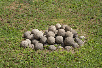 Image showing Old iron cannon balls on green grass