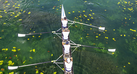 Image showing Men's quadruple rowing team on turquoise green lake