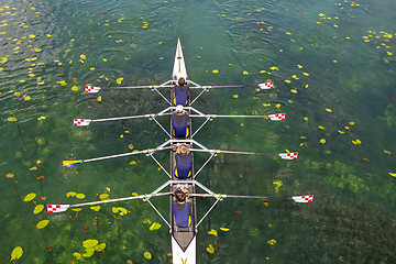 Image showing Men's quadruple rowing team on turquoise green lake