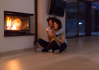 Image showing happy multiethnic couple sitting in front of fireplace