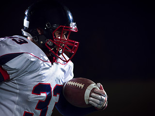 Image showing American football player holding ball while running on field