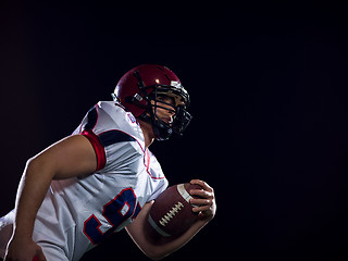 Image showing American football player holding ball while running on field