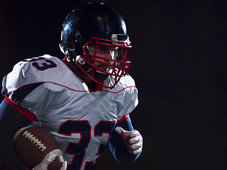 Image showing American football player holding ball while running on field