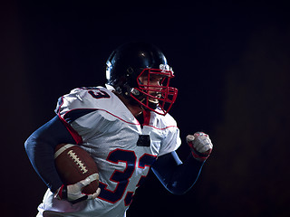 Image showing American football player holding ball while running on field