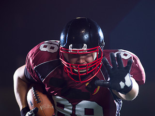 Image showing American football player holding ball while running on field