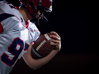 Image showing American football player holding ball while running on field