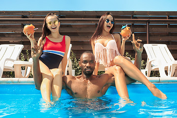 Image showing Group of friends playing and relaxing in a swimming pool during summer holidays