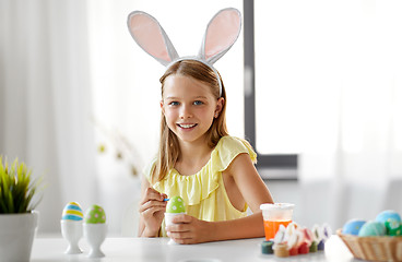 Image showing happy girl coloring easter eggs at home