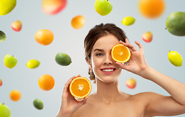 Image showing smiling woman with oranges over fruits background