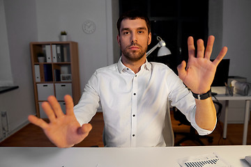 Image showing businessman using gestures at night office