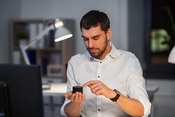 Image showing businessman using smart speaker at night office