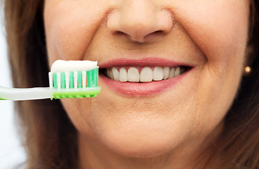 Image showing senior woman with toothbrush brushing her teeth