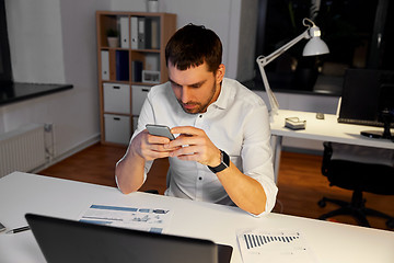 Image showing businessman with smartphone and computer at office