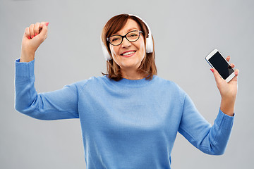 Image showing senior woman in headphones listening music on cell