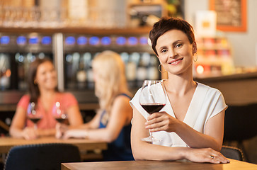 Image showing happy woman drinking red wine at bar or restaurant