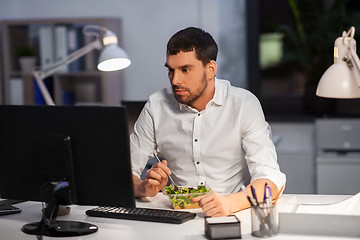 Image showing businessman with computer eating at night office