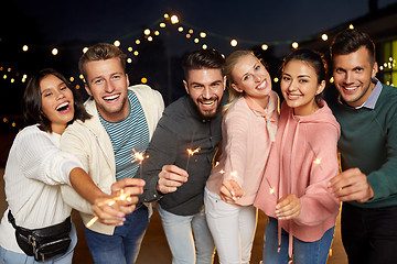 Image showing happy friends with sparklers at rooftop party