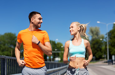 Image showing couple with fitness trackers running along bridge